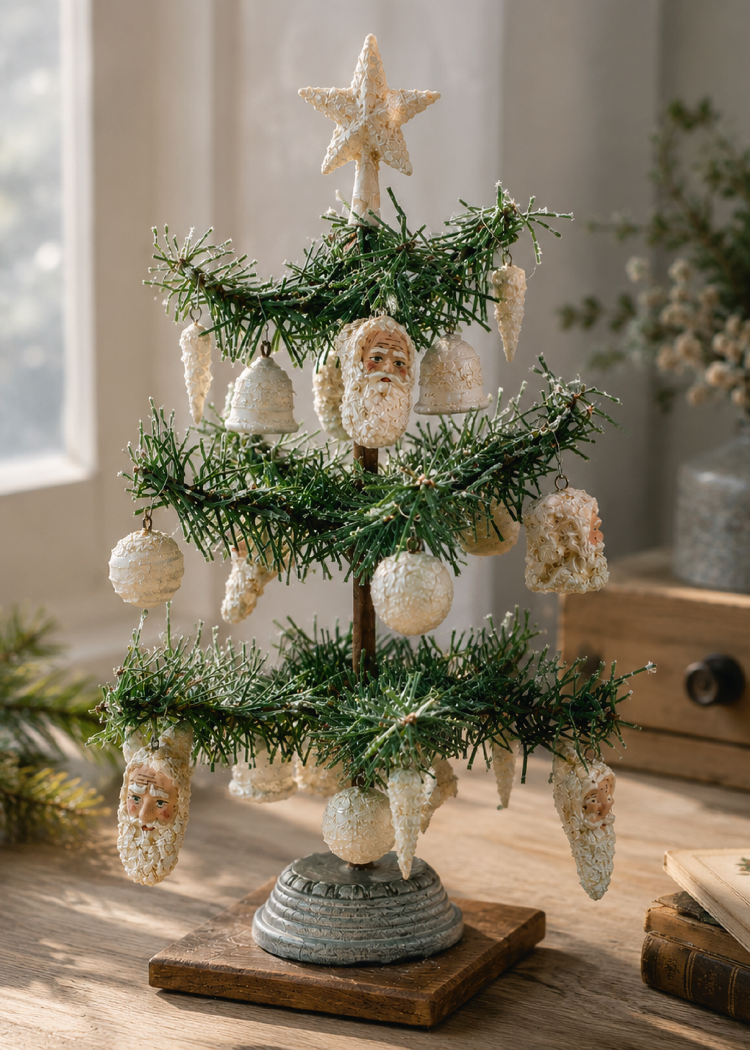 Kleiner künstlicher Weihnachtsbaum auf Holzsockel mit cremefarbenen Vintage-Anhängern wie Nikolausgesichtern, Kugeln und Zapfen, ideal als festliche Tischdekoration