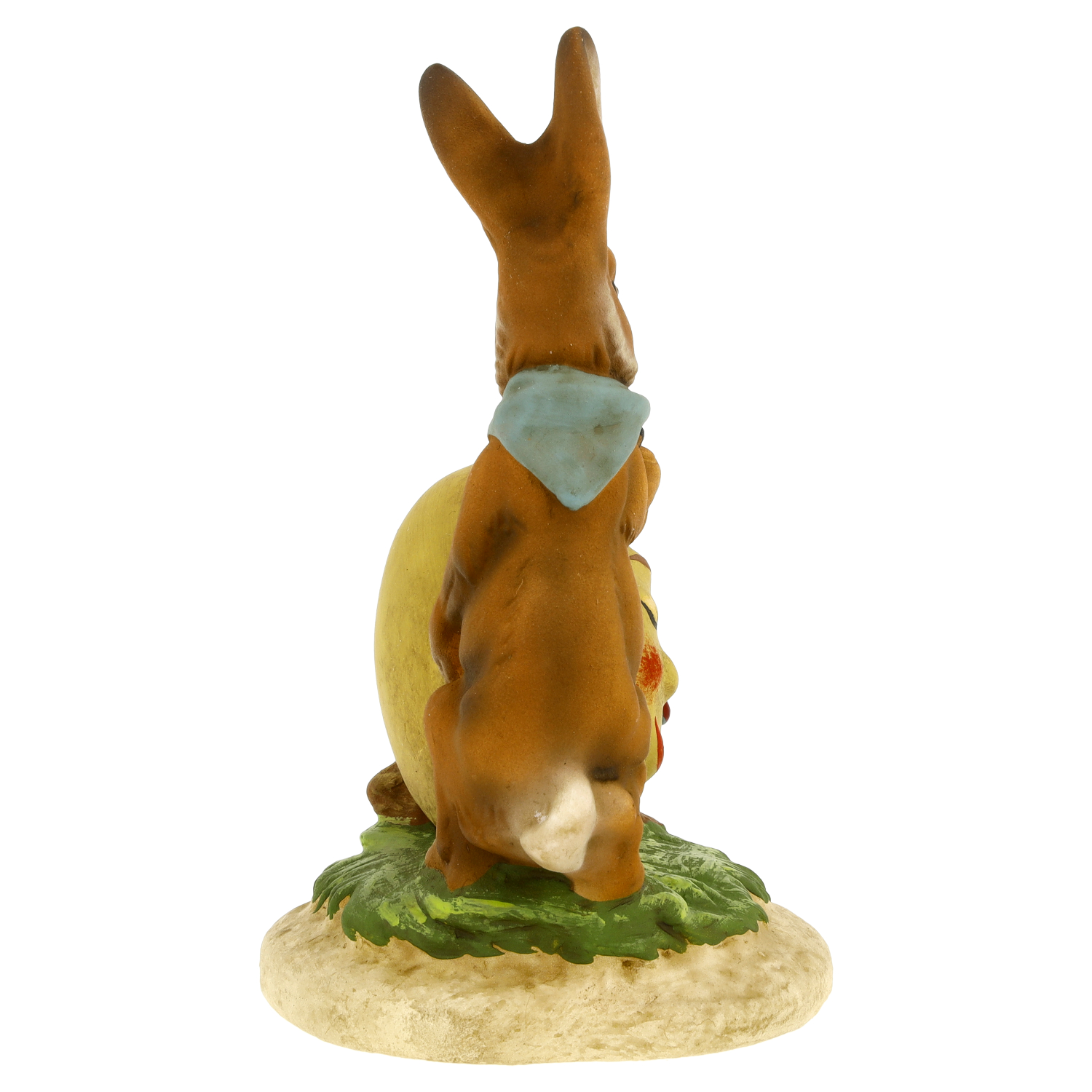 Rückansicht einer bemalten Osterhasen-Figur mit Halstuch neben einem großen Ei auf Sockel, Frühlingsdekoration