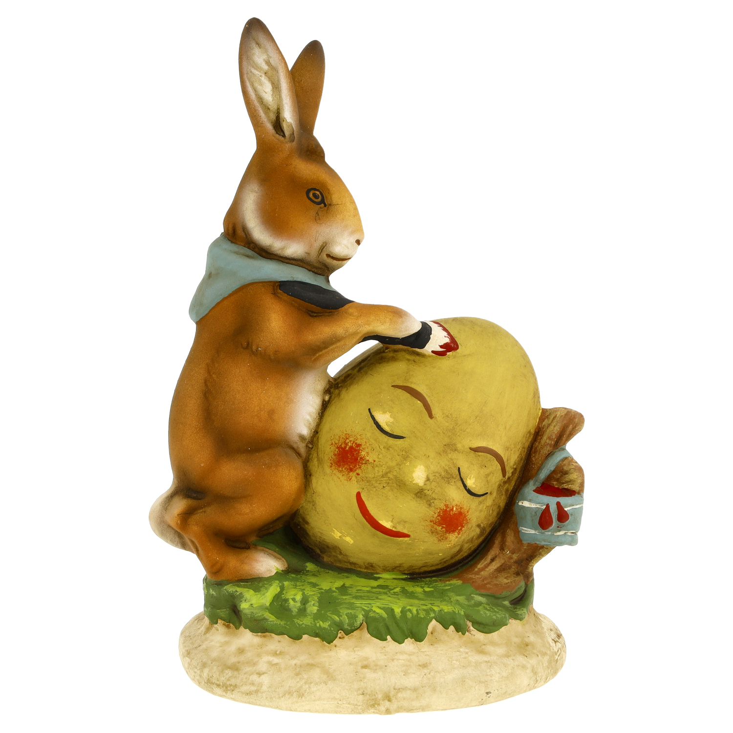 Dekofigur: brauner Osterhase mit blauem Schal bemalt ein lächelndes Osterei, nostalgischer Stil, auf Sockel.